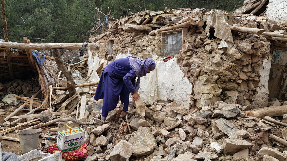 Women searches through rubble after earthquake in Afghanistan
