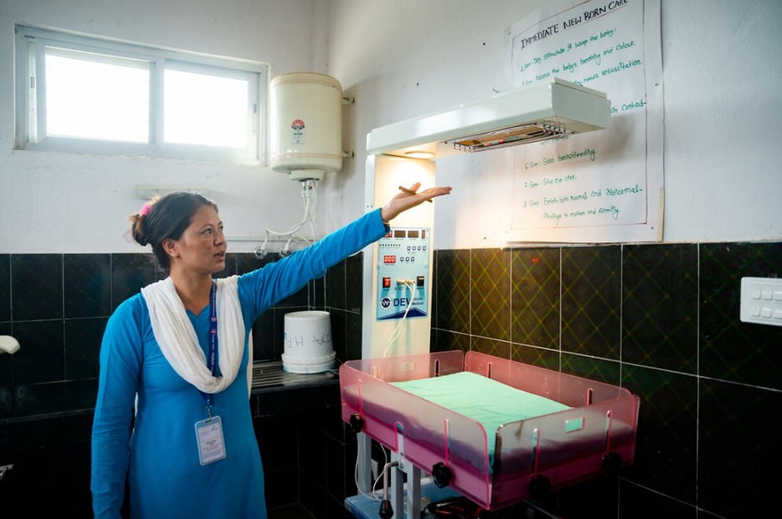 Nurse Radha Thapa demonstrates a new heat lamp at the Patariya's birthing center, an example of the health post's improvements made as a result of the CS:MAP activity.