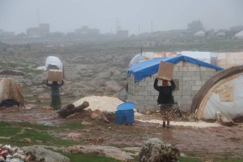 Displaced Syrians carrying assistance to their tents in Northwest Syria, winter 2020.