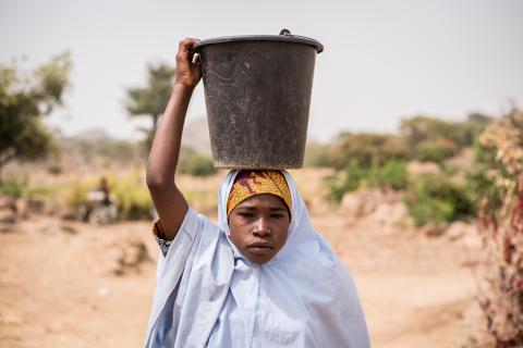 Rafiat (12) carries water in a bucket on her as she walks back home after collecting water from the stream in Kissa community, Kwaja village, Adamawa, Nigeria.