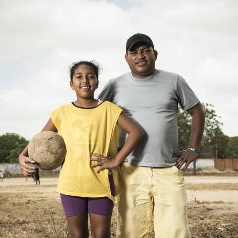 Heloilson and his daughter, Thayssa, pose by a soccer field in Brazil.