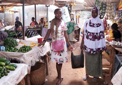 Floriane (left), age 18, strolls through a local market with one of the displaced women.