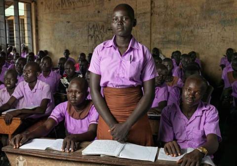 Hellena stands in her classroom in South Sudan. “[When my family and I] eat only once a day, in the evening,” she says. “But in the morning and lunch time, we don’t eat. … we eat pumpkin leaves, it’s the only plant that survived the drought, but it doesn’t bear any fruit.”